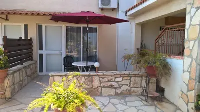 a patio with a table and an umbrella at Rantzo Holiday Apartments in Pissouri