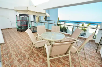 a balcony with a table and chairs and an umbrella at Seafront Protaras Apartments in Protaras