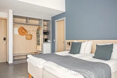 a bedroom with a large white bed with blue pillows at Sunprime Protaras Beach - Adults Only in Protaras