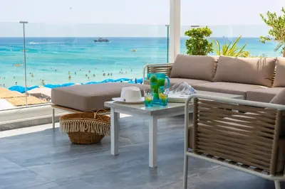 a living room with a couch and a table and the beach at Sunprime Protaras Beach - Adults Only in Protaras