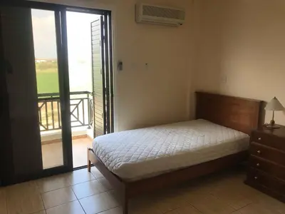 a bedroom with a bed and a door to a balcony at Limni Pool House B in Larnaka