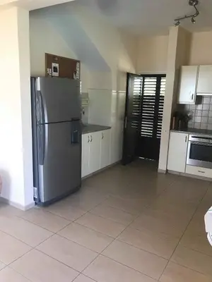 a kitchen with a stainless steel refrigerator and white cabinets at Limni Pool House B in Larnaka