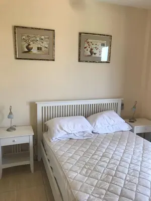 a bedroom with a bed with two tables and two pictures on the wall at Limni Pool House B in Larnaka