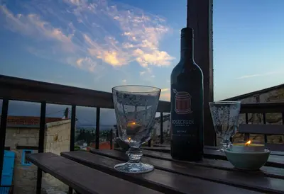 a bottle of wine and two glasses on a table at Dolphin Guest House and Studios in Tochni