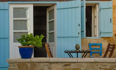 a blue house with a table and chairs on a porch at Dolphin Guest House and Studios in Tochni