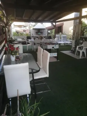 a patio with white chairs and a table with green carpet at Andros Residence in Limassol
