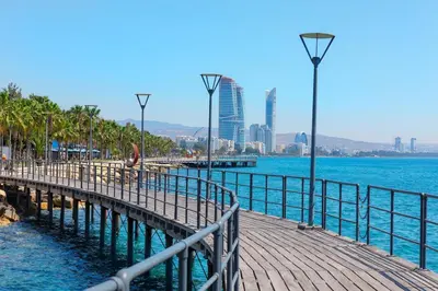 a wooden pier next to the water with a city at Delphi Court - large 1 bed -sleeps 4, Near sea/beach - free wifi in Limassol