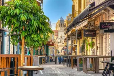 a city street with tables and trees and buildings at Delphi Court - large 1 bed -sleeps 4, Near sea/beach - free wifi in Limassol