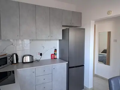 a kitchen with gray cabinets and a refrigerator at Delphi Court - large 1 bed -sleeps 4, Near sea/beach - free wifi in Limassol