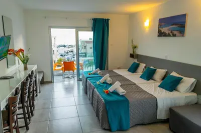 a bedroom with a bed in a room with a balcony at A Maos Hotel Apartments in Ayia Napa