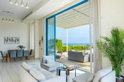 a living room with white furniture and a large glass door at Infinity Villa in Protaras