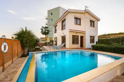 a swimming pool in front of a house at Buena Vista Villa in Protaras
