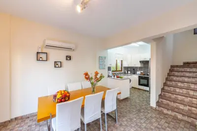 a kitchen and dining room with a wooden table and white chairs at Buena Vista Villa in Protaras