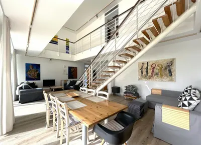 a living room with a table and a staircase at Art by PraXis in Governors Beach