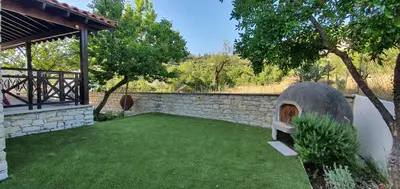 a backyard with a stone wall and a green lawn at Lefkara Villa in Kato Lefkara
