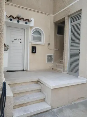 a house with a white door and stairs in front of it at Elena Holiday Apartment in Larnaka