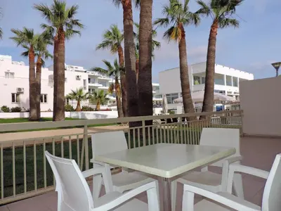 a table and chairs on a balcony with palm trees at La Casa Di Napa Apartments in Ayia Napa