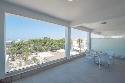 a balcony with a table and chairs and a large window at La Casa Di Napa Apartments in Ayia Napa