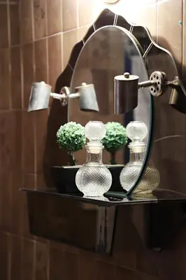 a shelf with two glass bottles and flowers in front of a mirror at Maria Court 2, Apt 32 in Larnaka