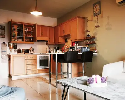 a kitchen with wooden cabinets and a table with chairs at Ria Court 33 in Larnaka