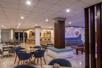 a restaurant with tables and chairs and a fireplace at Seagull Hotel Apartments in Protaras