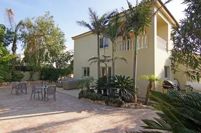 a building with tables and chairs and palm trees at Villa Cleopatra in Ayia Napa