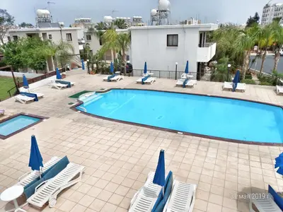 a swimming pool with lawn chairs and umbrellas at Maricosta Apartments in Protaras