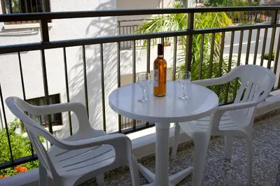 a white table with two glasses and a bottle of wine at Maricosta Apartments in Protaras