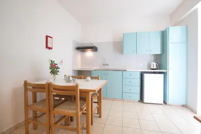 a kitchen with blue cabinets and a table and chairs at DebbieXenia Hotel Apartments in Protaras