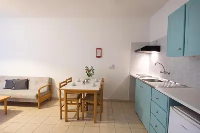 a kitchen with blue cabinets and a table with cups on it at DebbieXenia Hotel Apartments in Protaras