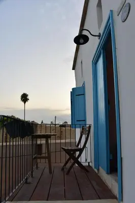 a wooden deck with a table and a bench and a door at Athieno - Αθηαινώ in Athienou
