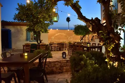 a patio with tables and chairs and a building at Athieno - Αθηαινώ in Athienou