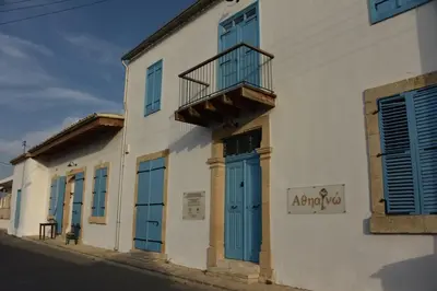 a white building with blue doors and a balcony at Athieno - Αθηαινώ in Athienou