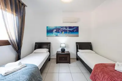 two twin beds in a room with a table at Sea Front Oceanus H3 by Ezoria Villas in Ayia Napa