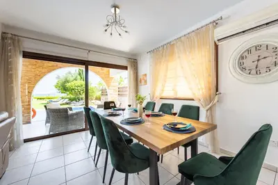 a dining room with a wooden table and green chairs at Sea Front Oceanus H3 by Ezoria Villas in Ayia Napa