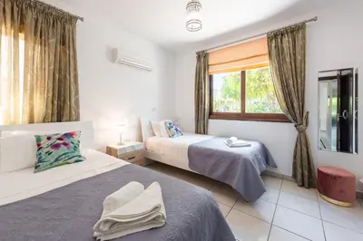 a bedroom with two beds and a window at Sea Front Oceanus H3 by Ezoria Villas in Ayia Napa