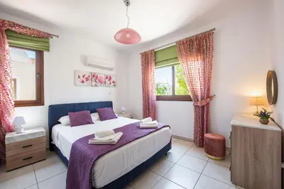 a bedroom with a bed and two windows at Sea Front Oceanus H3 by Ezoria Villas in Ayia Napa