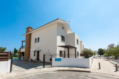 a white house with a fence in front of it at Sea Front Oceanus H3 by Ezoria Villas in Ayia Napa