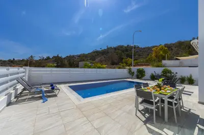 a patio with a table and chairs next to a pool at Protaras Villa Araella in Ayia Napa