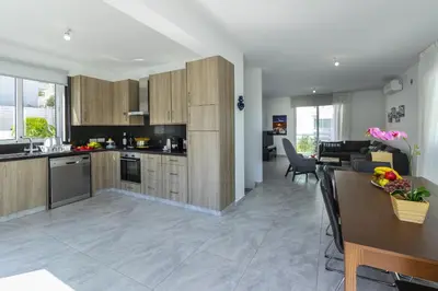 a kitchen with wooden cabinets and a dining room at Protaras Villa Araella in Ayia Napa