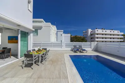 a patio with a table and chairs next to a pool at Protaras Villa Araella in Ayia Napa