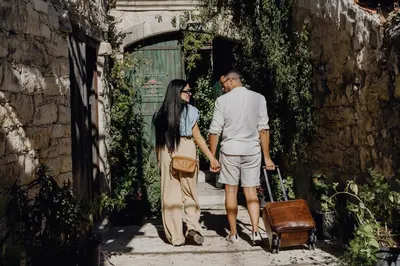 a man and woman standing in an alley with a suitcase at Oinou Strata - Adults Only in Vouni