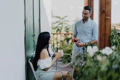 a man and a woman sitting on a porch with drinks at Oinou Strata - Adults Only in Vouni