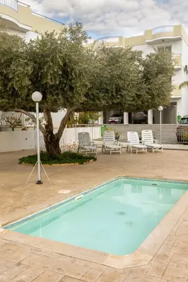 a pool in a courtyard with chairs and a tree at Oceania Bay Village in Pyla
