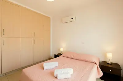 a bedroom with a pink bed and two towels at Oceania Bay Village in Pyla