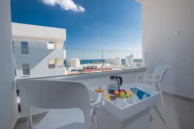 a balcony with a table and chairs and a view of a city at Kokkinos Boutique Hotel in Protaras
