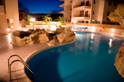 a large swimming pool in a hotel at night at Mediterranean Sunrise Complex in Voroklini