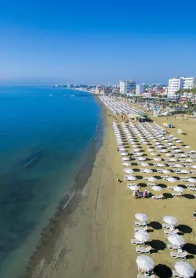 a beach with a bunch of umbrellas and the ocean at By The Way Apartment in Larnaka