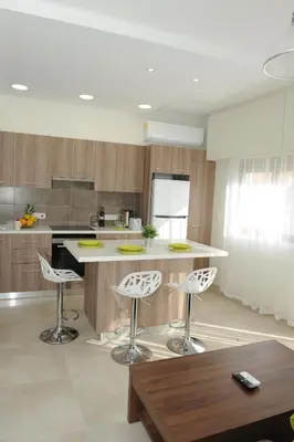 a kitchen with two bar stools and a counter at By The Way Apartment in Larnaka