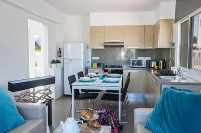 a kitchen with a table and chairs in a kitchen at Nicholas Seaview Apartments in Protaras